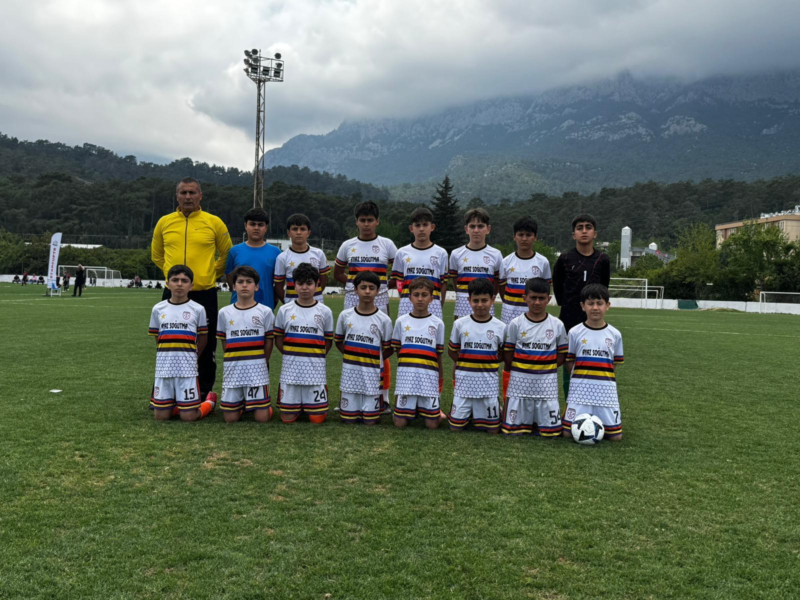 U11 2015 yaş grubu dağ manzaralı sahada beyaz forma takım fotoğrafı